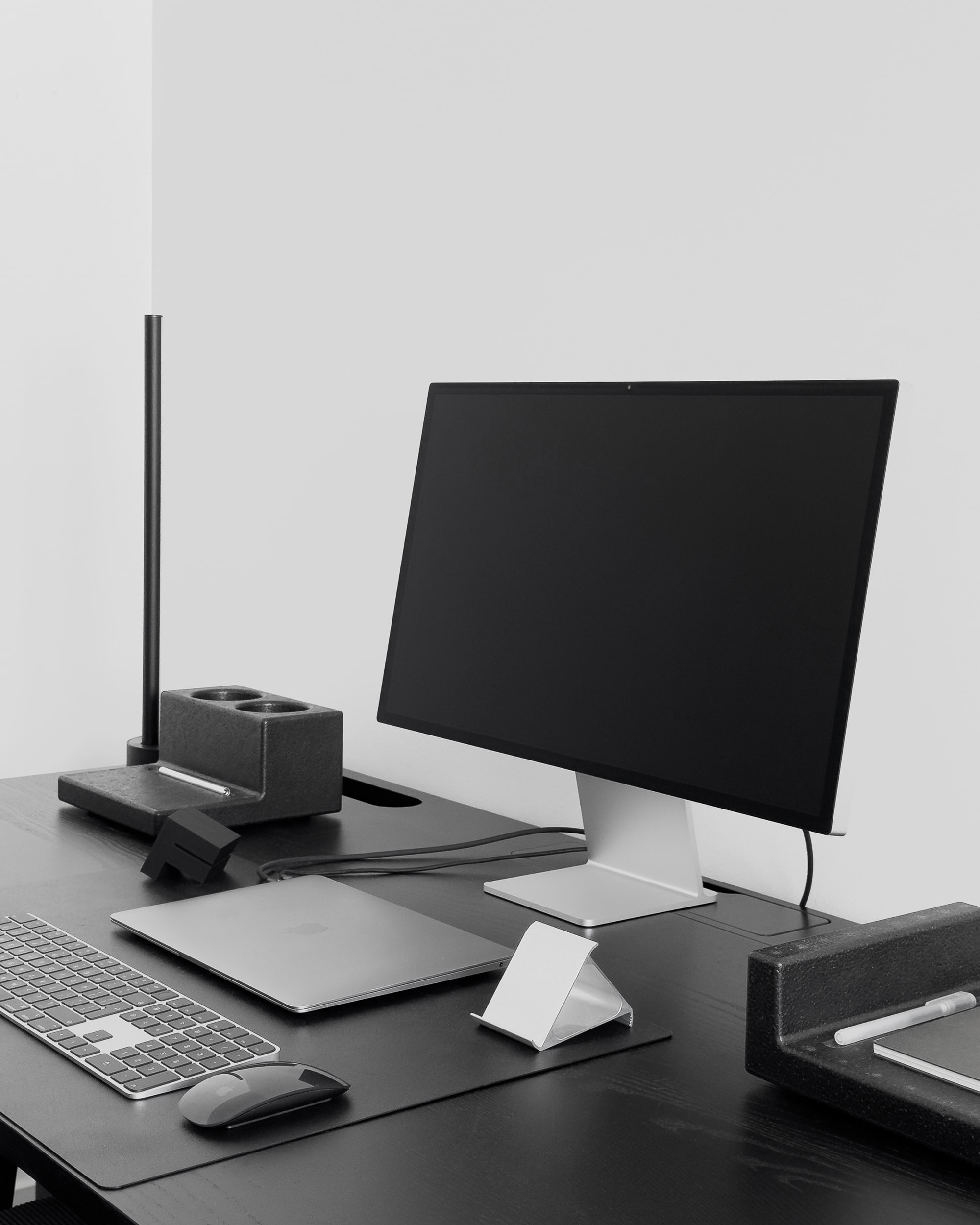 minimal desk setup with keyboard, laptop, monitor, and trays